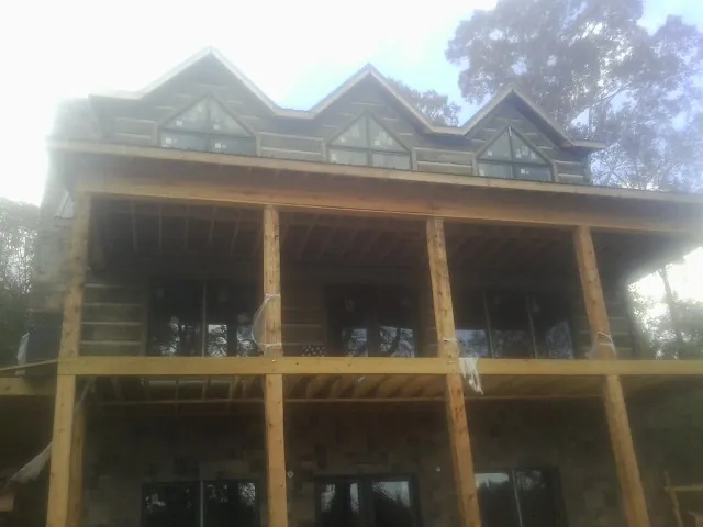 Dormers and porch framing on a large log home under construction — Roof Coating work by our crew in Pattison