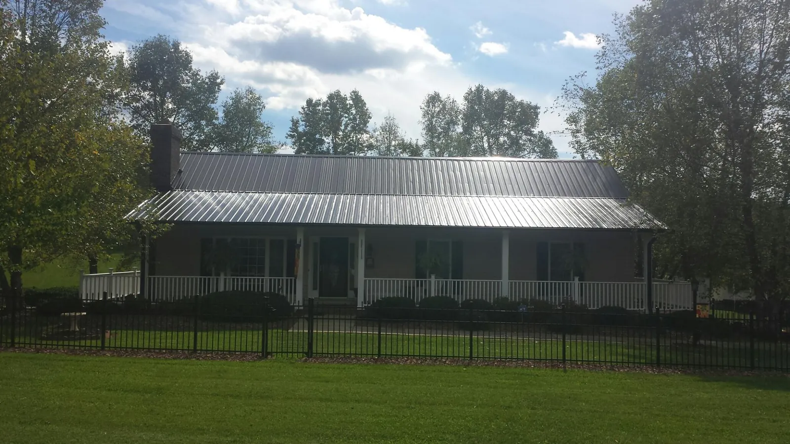 Gray metal roof on a brick ranch with a full width front porch — Gutter Guard Installation work by our crew in Pattison