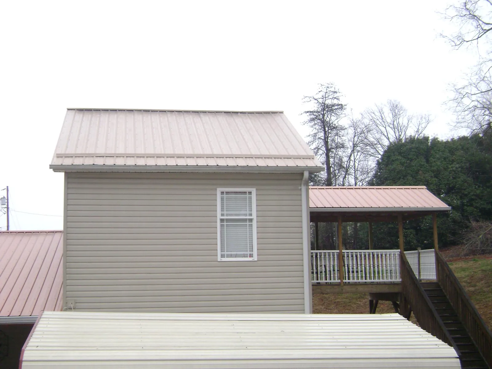 Tan metal roofs on a two story addition and attached porch, from a Roof Replacement job in Pattison