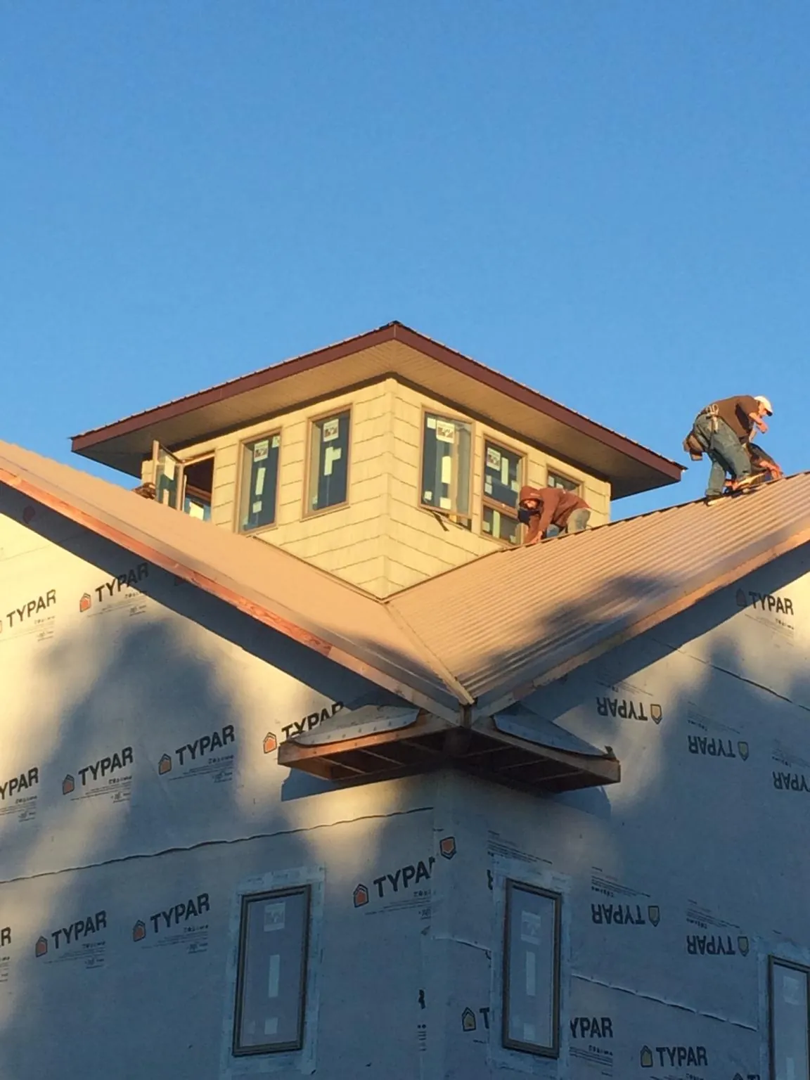 Roofers working around a rooftop cupola on a new metal roof at sunset — Roof Waterproofing in Pattison by Roofing Brothers